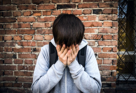 Vignetting Photo of Sad Teenager by the Brick Wallの写真素材