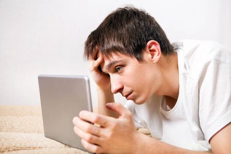 Sad Young Man with Tablet Computer at the Homeの写真素材