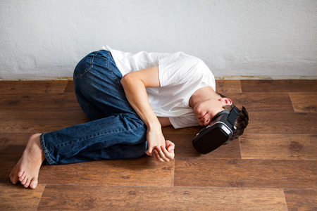 Young Man sleep in Virtual Reality Headset on the Floor in the Room