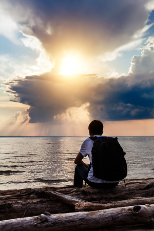 Young Man Silhouette at the Sunset on the Sea Backgroundの写真素材