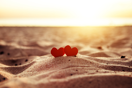 Toned Photo of Two Red Hearts in the Sand at the Evening Beachの写真素材