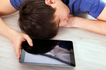 Young Man sleep on the Table with a Tablet Computerの写真素材