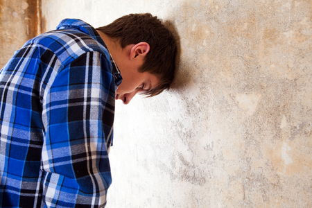 Sad Young Man by the Old Wallの写真素材