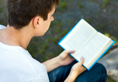 Young Man read a Books on the City Streetの写真素材