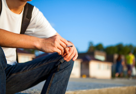 Person sit with Cigarette on the City Streetの写真素材