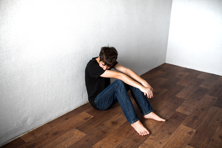 Sad Young Man on the Floor in the Roomの写真素材