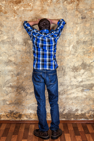 Rear View of the Sad Young Man by the Old Wallの写真素材