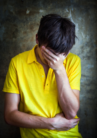 Vignetting Photo of Sad Young Man by the Old Wallの写真素材