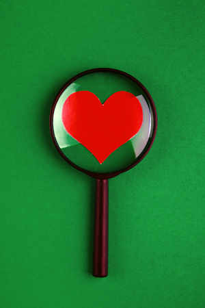 Heart Shape in the Magnifying Glass on the Green Paper Backgroundの写真素材