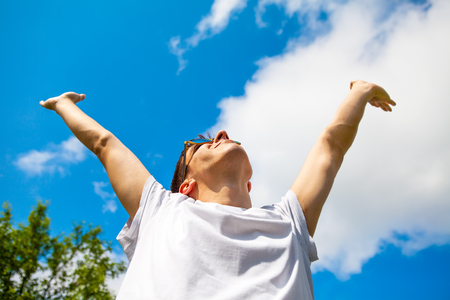 Happy Man with Hands Up on the Sky Backgroundの写真素材