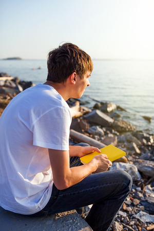 Pensive Young Man with a Book at the Seasideの写真素材