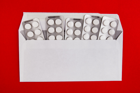 Pills with an Envelope on the Red Paper Background closeupの写真素材