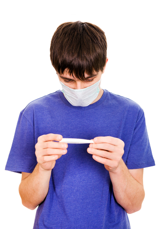 Sad Young Man in Flu Mask check the Thermometer Isolated on the White Backgroundの写真素材