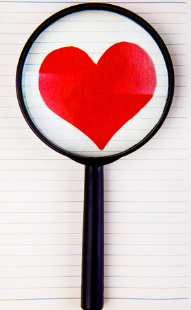 Heart Shape and Magnifying Glass on the Writing Pad Backgroundの写真素材