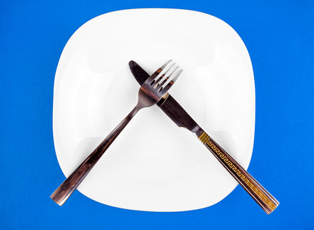 Empty Plate with a Cutlery on the Blue Paper Backgroundの写真素材