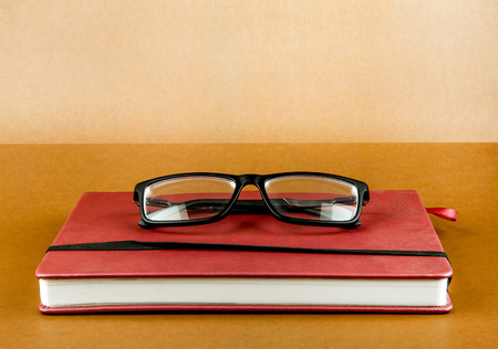 Red Book with a Glasses on the Brown Paper Background closeup