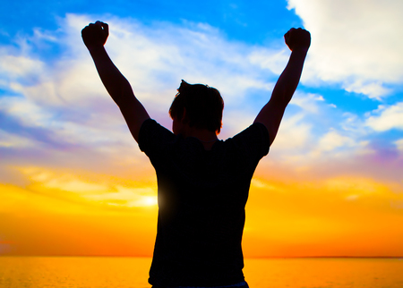 Happy Person Silhouette at the Sunset on the Sea Backgroundの写真素材