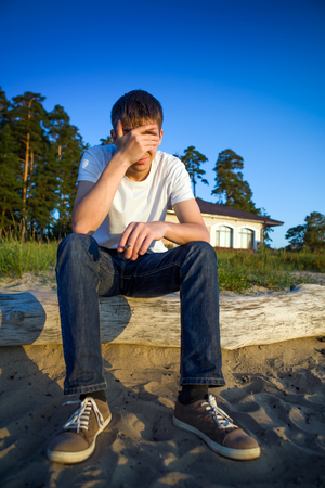 Sad Young Man sit on the Log on the Nature Backgroundの写真素材