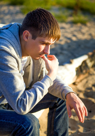 Pensive Young Man sit on the Log on the Nature Backgroundの写真素材