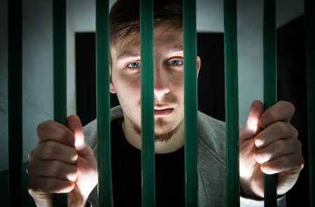 Jailed Young Man behind bars in a Cellの写真素材