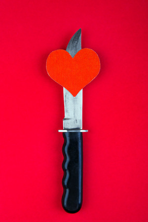Heart Shape and a Knife on the Red Paper Backgroundの写真素材