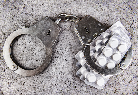 Pills with a Handcuffs on the Grunge Metal Background closeupの写真素材