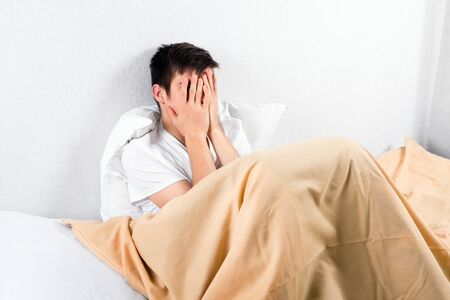 Sad Young Man in the Bed by the Wallの写真素材