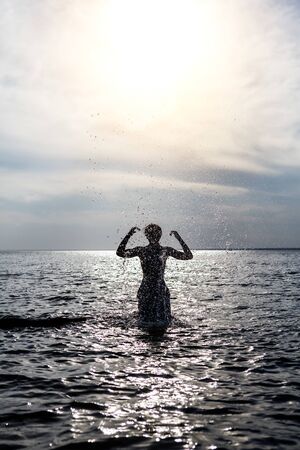 Man Silhouette with splashes in the Water on the Sunset Backgroundの写真素材