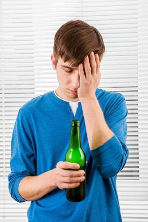 Sad Young Man with a Beer on the Jalousie Backgroundの写真素材
