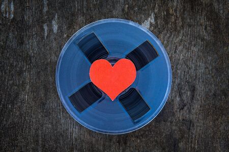 Vintage Reel with a Tape and with Red Heart on the Grunge Background closeupの写真素材