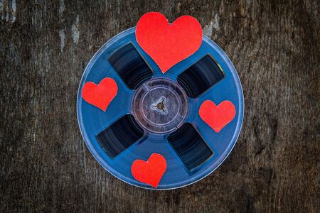Vintage Reel with a Tape and with Red Hearts on the Grunge Background closeup