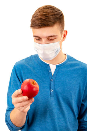 Young Man in a Flu Mask hold an Apple Isolated on the White Backgroundの写真素材
