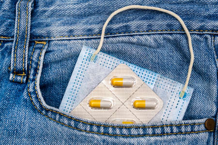 Medical Flu Mask and a Pills in a Jeans Pocket closeupの写真素材