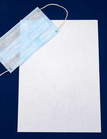 Medical Flu Mask on the Empty Paper on the Blue Fabric Background closeupの写真素材