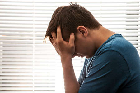 Sad Young Man in the Room on the Jalousie Background