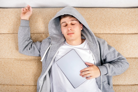 Young Man sleep with a Tablet Computer on the Sofa at the Home