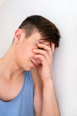 Sad Young Man in Undershirt by the White Wall closeup