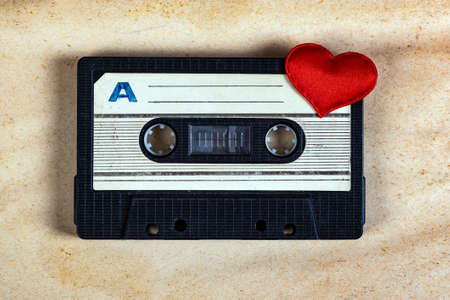 Old Audio Cassette with a Red Heart on the Old Paper Background closeupの写真素材