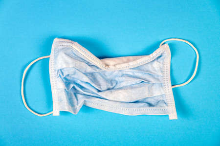 Used Flu Mask on the Blue Paper Background closeupの写真素材