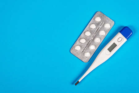 Pills with a Thermometer on the Blue Paper Background closeupの写真素材