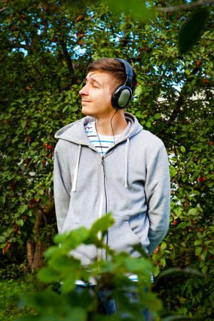 Young Man in Headphones listen to the Music in the Summer Gardenの写真素材