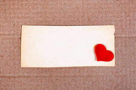 Old Blank Paper with a Red Heart on the Cardboard Backgroundの写真素材