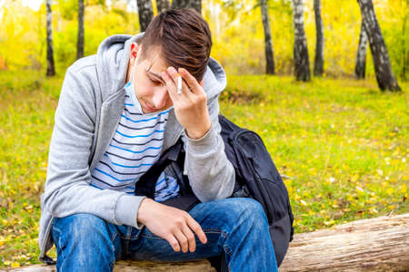 Sad Young Man with a Cigarette sit on the Log in the Autumn Forestの写真素材