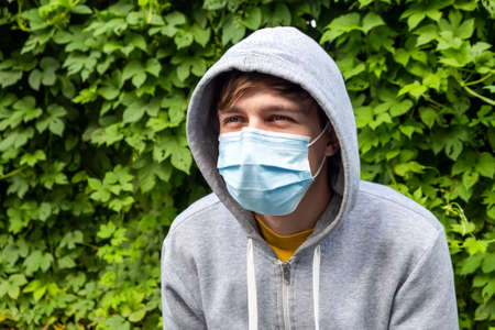 Young Man in the Flu Mask on the Green Leaves Background