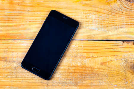 Mobile Phone with a Blank Screen on the Wooden Planks Background closeup