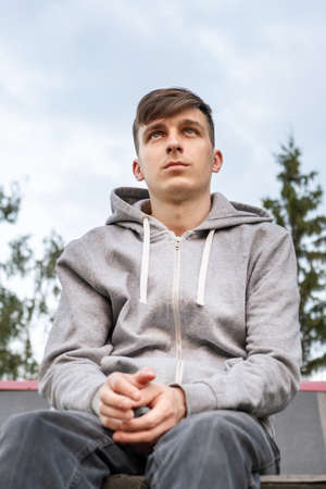 Sad Young Man on the Sky Background outdoorの写真素材