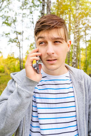 Young Man with a Mobile Phone in the Autumn Forest