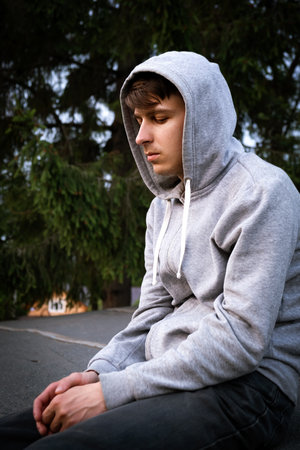 Sad Young Man Portrait in a Hoodie on the Nature Background