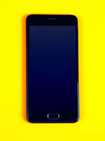 Mobile Phone with a Blank Screen on the Yellow Paper Background closeupの写真素材