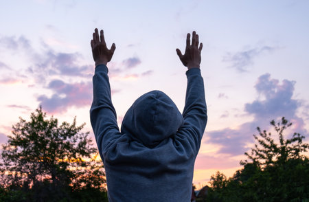 Man with Hands Up on the Evening Sky Backgroundの写真素材